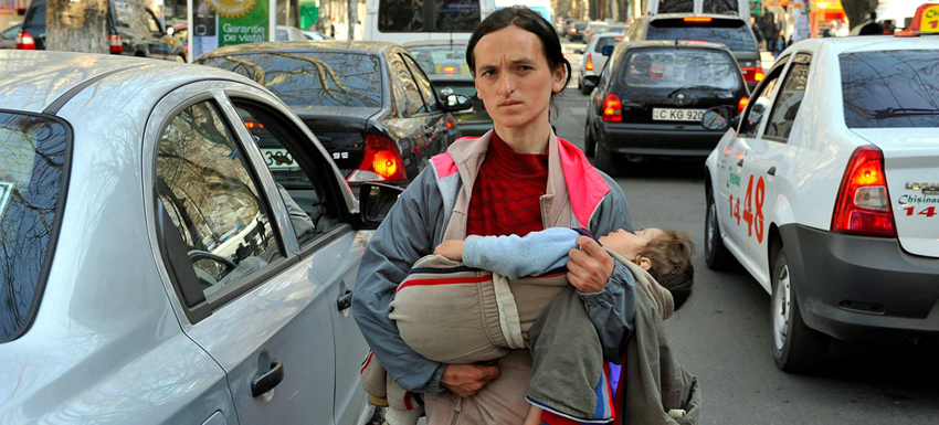 A woman carries her child while begging on the streets of Chisinau in Moldova. ILO/Marcel Crozet
 
